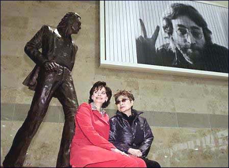 Yoko Ono and the Prime Minister's wife sit in front of the John Lennon statue at the John Lennon Liverpool Airport.